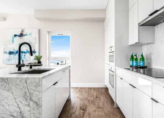 a kitchen with marble counter tops and white cabinets  at Oslo, Seattle, 98102