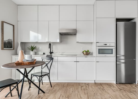 a white kitchen with a small table and a refrigerator  at Oslo, Seattle, 98102