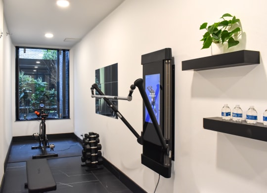 a gym with a treadmill and a tv in a room with a window  at Oslo, Seattle, Washington