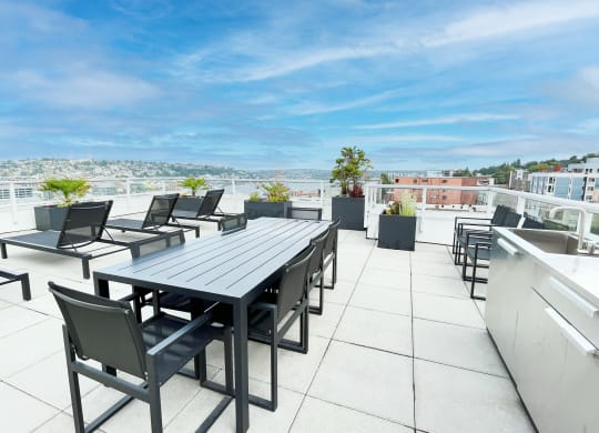 a patio with a table and chairs on a roof  at Oslo, Seattle, WA, 98102