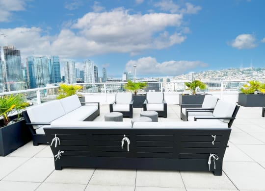 a lounge area on the roof of a building with a city in the background  at Oslo, Seattle, 98102