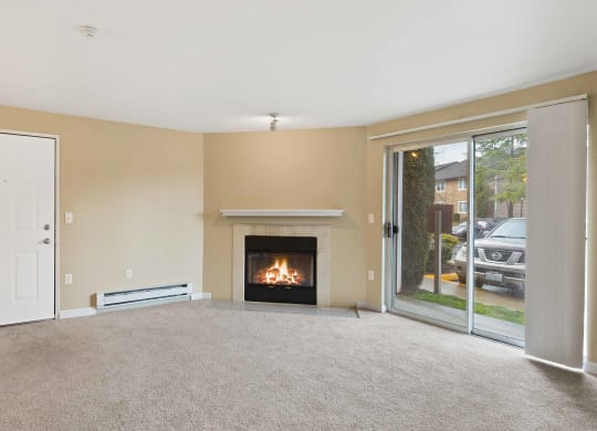 an empty living room with a fireplace and a glass door at Quartz Creek, Mountlake Terrace, Washington