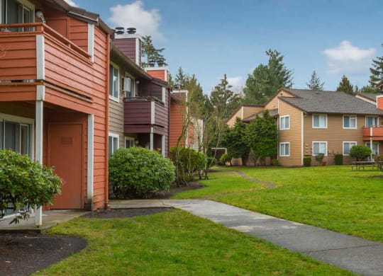 a walkway between two apartment buildings with grass and trees at Quartz Creek, Mountlake Terrace, WA, 98043