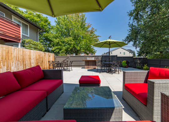 a backyard patio with red couches and a glass table at Quartz Creek, Mountlake Terrace, WA, 98043