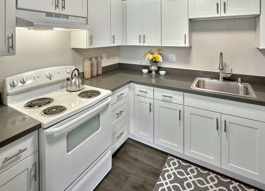 a kitchen with white cabinets and a white stove and sink at Quartz Creek, Mountlake Terrace