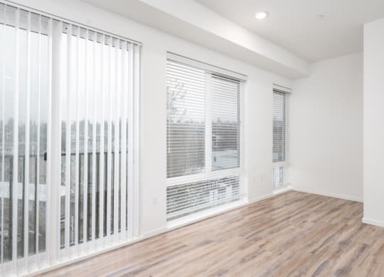 an empty living room with large windows and a wood floor at The Loop at Green Lake, Washington