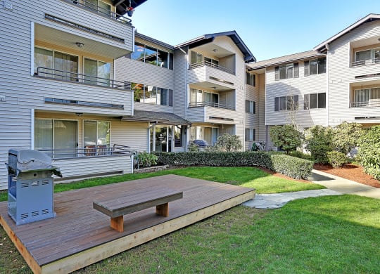 a backyard with a picnic table in front of an apartment building  at Townside Flats, Redmond, WA