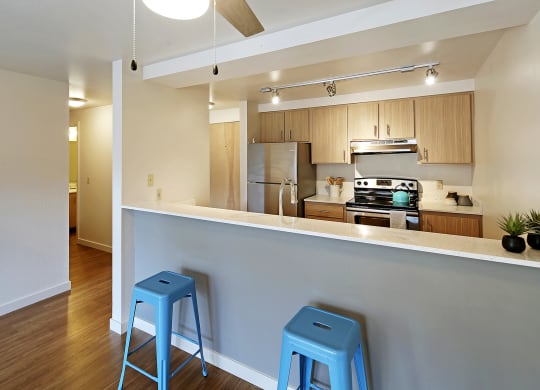 a kitchen with two blue stools in front of a bar with a counter top  at Townside Flats, Redmond