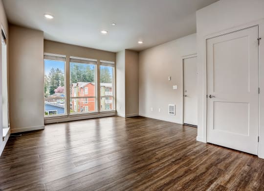 an empty living room with a large window and wooden floors at Woodcreek, Poulsbo