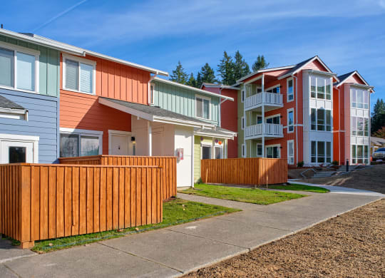 a row of colorful homes in front of a sidewalk at Woodcreek, Poulsbo
