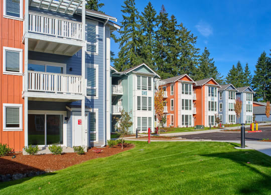 an exterior view of a row of apartment buildings with green grass at Woodcreek, Poulsbo Washington