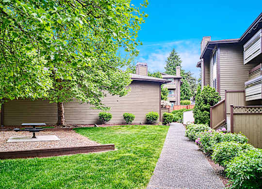 A backyard with a picnic table and a concrete path at apartments in Renton, WA.