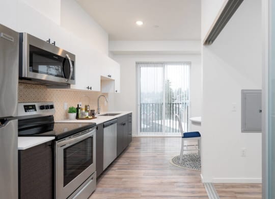 a kitchen with stainless steel appliances and a door to a balcony