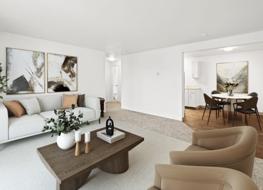 A bright living room with taupe carpets, white walls and staged with a white couch, a coffee table, two chairs and wall art.at North Pointe, Post Falls, ID