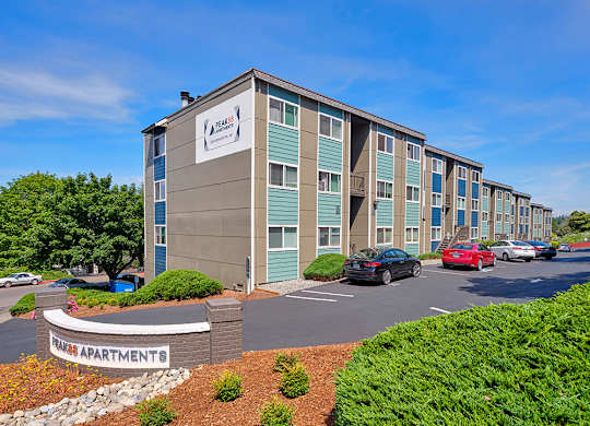 Exterior apartments with green bushes and trees and on-site community parking.