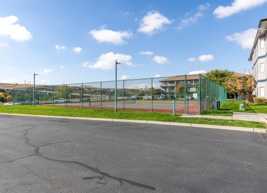 a tennis court in front of a building with a green fence  at Shoreline Village, Richland