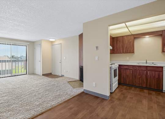 A spacious living room with a kitchenette and sliding glass doors.
