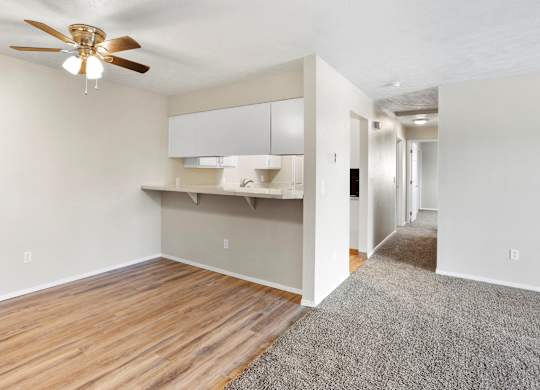 Bright dining space with a ceiling fan, white walls, and carpeted flooring at The Overlook at Falls Park Apartments in Post Falls, ID.