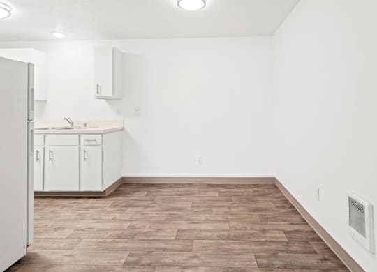 Bright dining area with faux wood floors and white walls. Kitchen with new white cabinets is visible to the left.at North Pointe, Post Falls, ID 83854