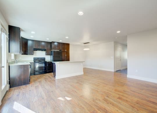 an empty living room and kitchen with wood flooring and black appliances at Copper Pines, Bozeman, MT