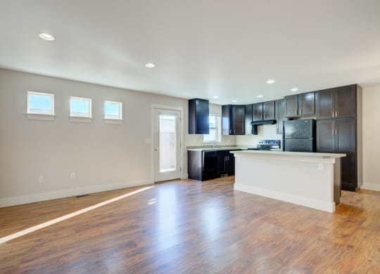 an empty living room and kitchen with wood flooring and black cabinets at Copper Pines, Bozeman, Montana