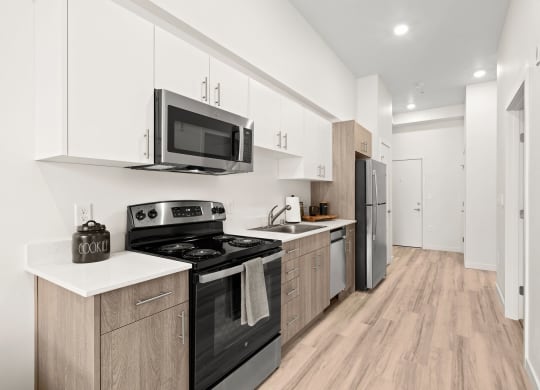 a kitchen with white cabinets and black appliances at The Duo, University Place, WA