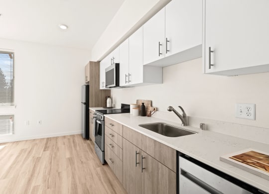 a renovated kitchen with white cabinets and a sink at The Duo, University Place, WA 98466