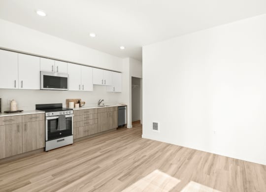 an empty kitchen with white walls and wood floors at The Duo, University Place, 98466