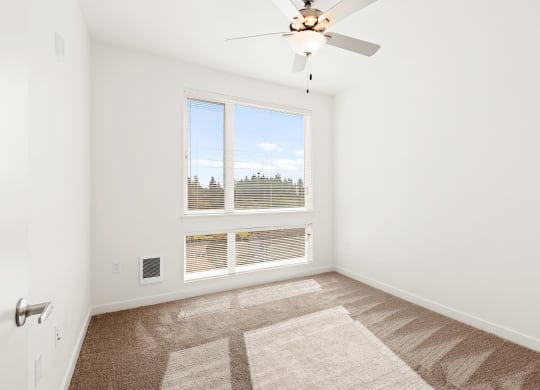 a bedroom with a large window and a ceiling fan at The Duo, University Place, WA