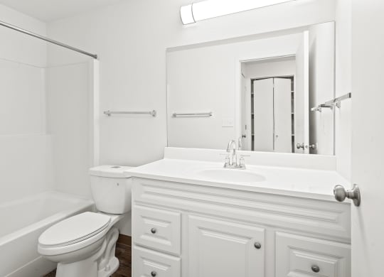 White bathroom with new white cabinets, large mirror, white toilet and full size bathtub.at North Pointe, Post Falls