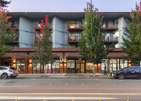 Building exterior at dusk with large green trees and balconies at 6 Wood Flats, Lacey Washington