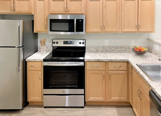 Corner style kitchen with wood cabinets and a stainless steel stove and microwave at 6 Wood Flats, Washington, 98503