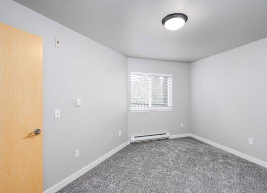 Large bedroom with plush carpet and bright window in a 728 square foot apartment at 6Wood Flats Lacey WA