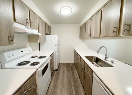 Double galley kitchen with oven, stovetop, fridge, sink, and dishwasher with a pass through window to the dining area.at The Trail, Snohomish, 98290