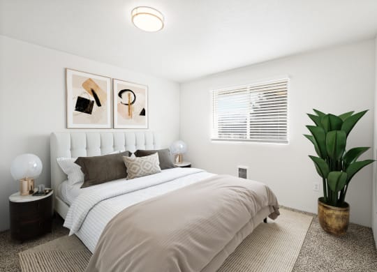 a large bedroom with white walls, taupe carpet, and a window on the back wall. Staged with queen-size bed, 2 side tables, art and a plant.at North Pointe, Post Falls