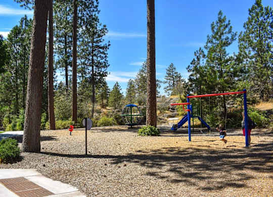 A playground with a red swing set and a stop sign in the background.