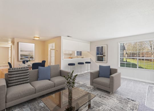Carpeted living room with view of kitchen and pass-through bar with stools. A large window looks out on a grass lawn.at Capitol Crossing, Olympia, WA