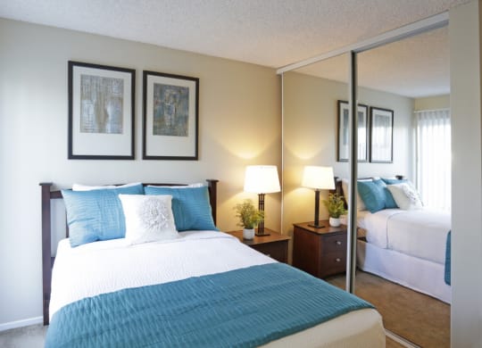 Bedroom with mirrored closet doors, full size bed and night stand  at Pacific Sands, San Diego, California