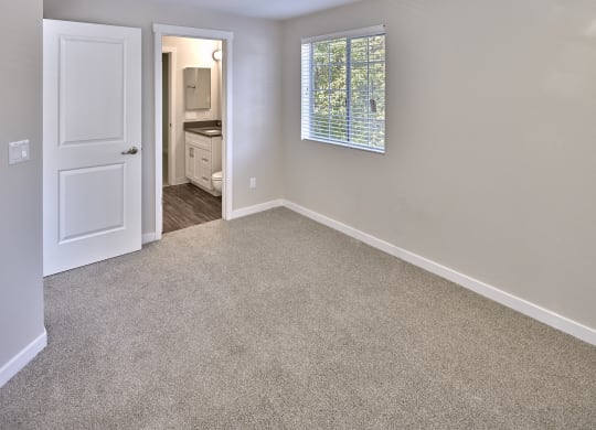 an empty room with carpet and a door to a bathroom