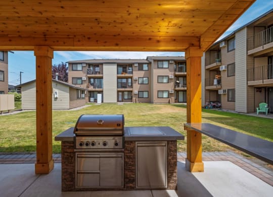 a barbecue grill is under a wooden pavilion surrounded by green grass. at Brix, Walla Walla