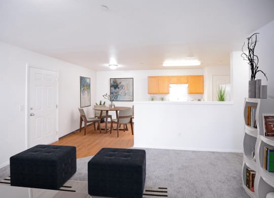 Big open living area with living room, dining area and kitchen with half wall visible. Taupe carpet in living room and faux wood flooring in dining and kitchen areas.at Canyon View, Idaho