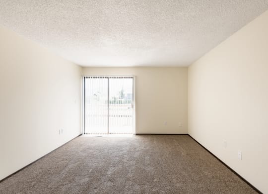 the spacious living room of an apartment with a large window