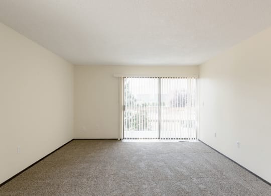 the spacious living room of an apartment with sliding glass doors