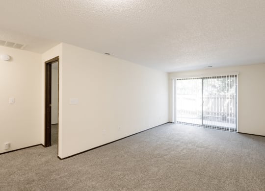 the spacious living room of an apartment with a large window