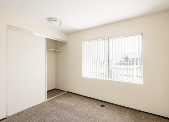 an empty living room with a large window and a closet