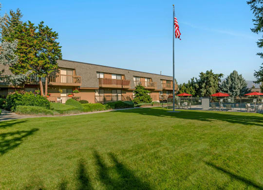 Grass courtyard with American Flag in center, swimming pool behind, and view of Beartooth Mountains.at Castlerock, Wenatchee, 98801