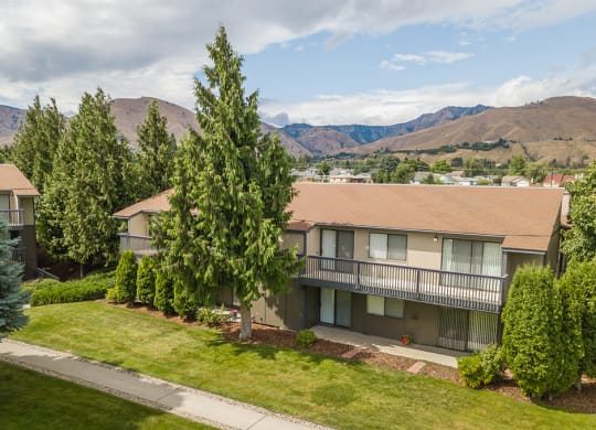Outside apartments with oversized balconies, grass area & trees below, and view of the Wenatchee Mountains.at Cedarwood, Wenatchee, WA