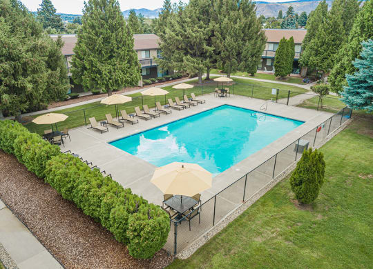 Large outdoor pool with ample pool seating and fence surrounding it.at Cedarwood, Wenatchee