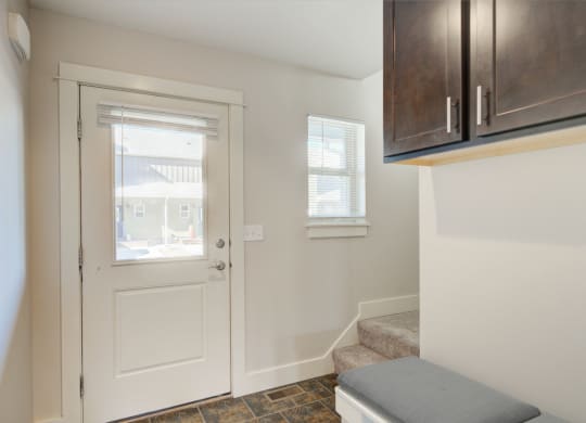 an entryway with a white door with a window and a staircase with a bench at Copper Pines, Montana