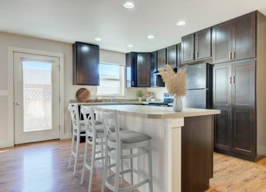 a kitchen with a large island with bar stools and dark wood cabinets at Copper Pines, Bozeman, MT